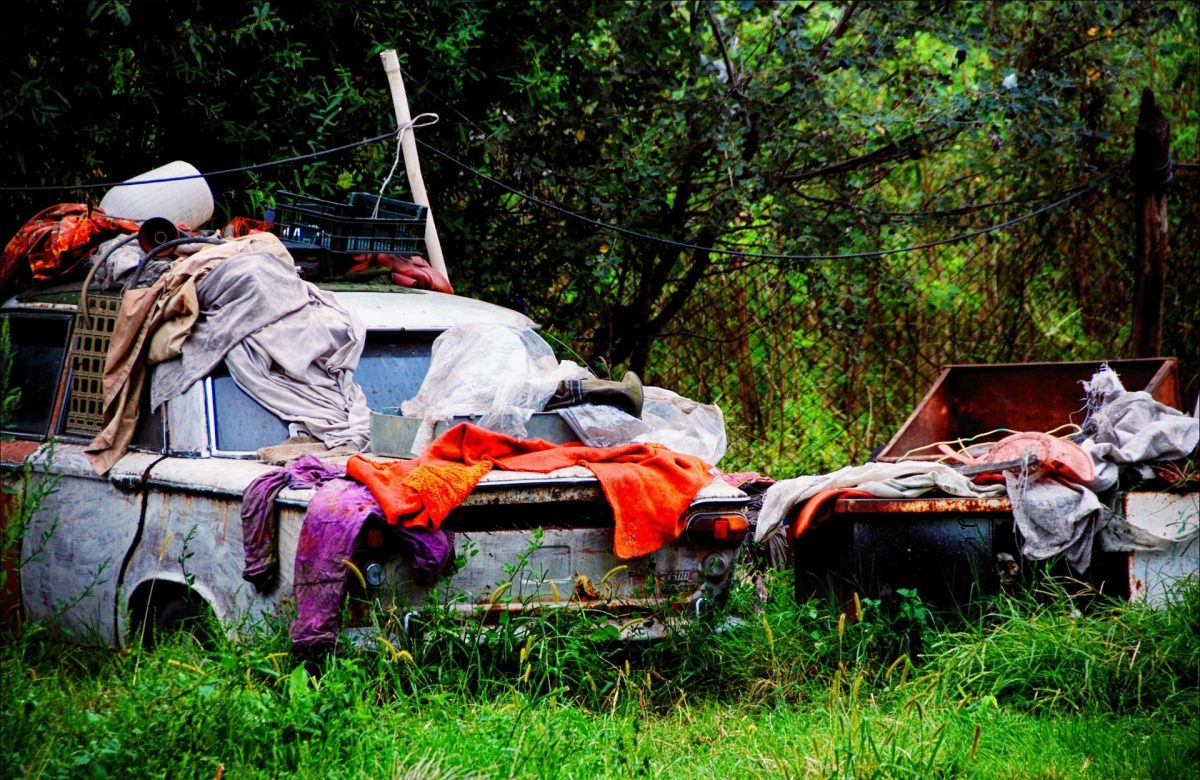 various clothing debris scattered across old rusted trucks in a yard
