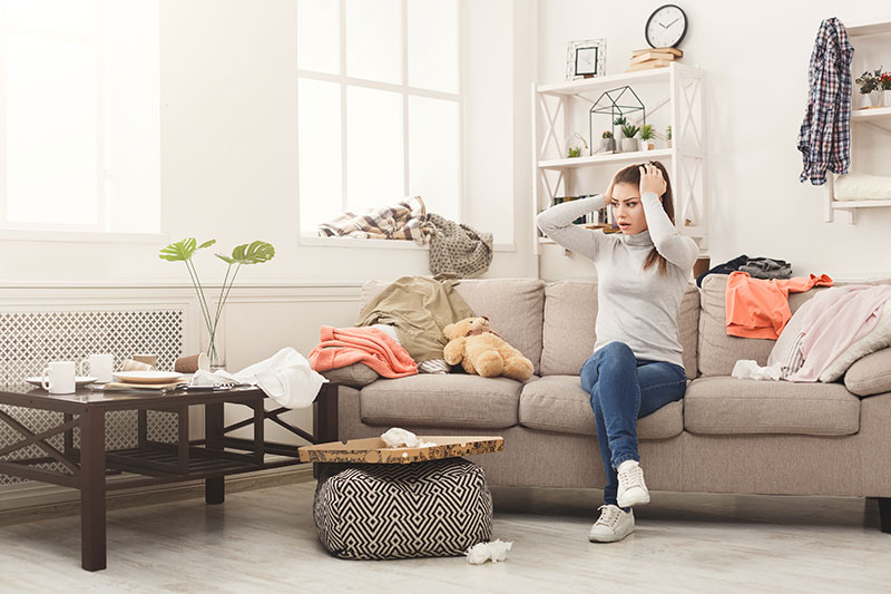 woman overwhelmed and needs help to declutter the room