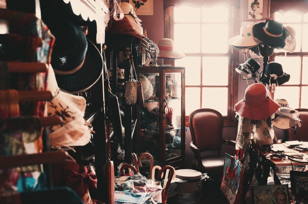 dressing room belonging to someone with a slight hoarding problem with many coat racks and hat racks full of items and all surfaces covered in things